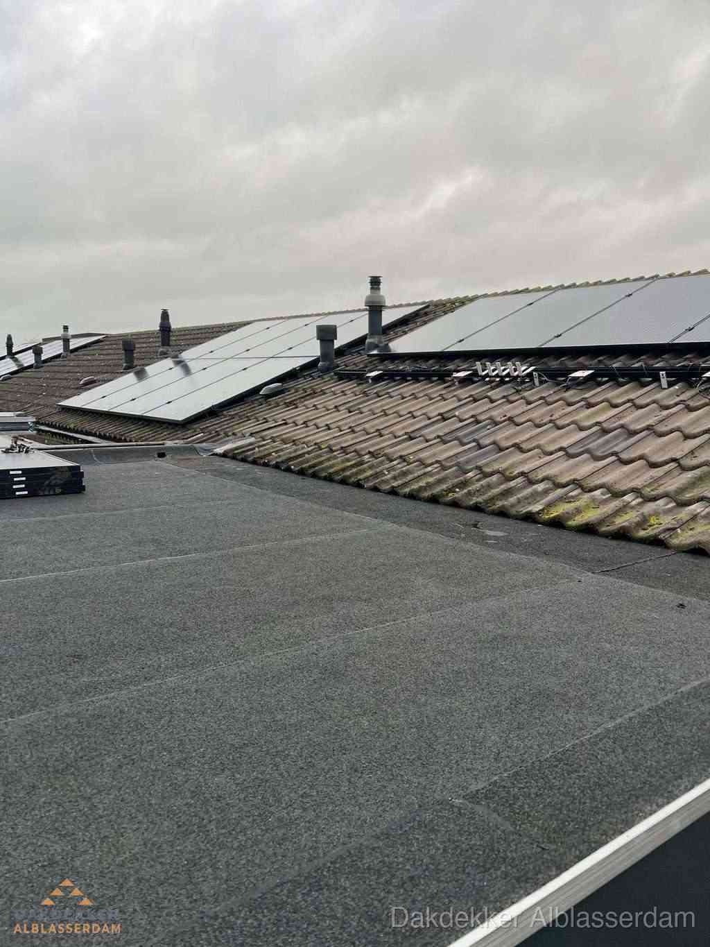 Plat dak inspectie met bitumen bedekking naast schuin pannendak in Alblasserdam