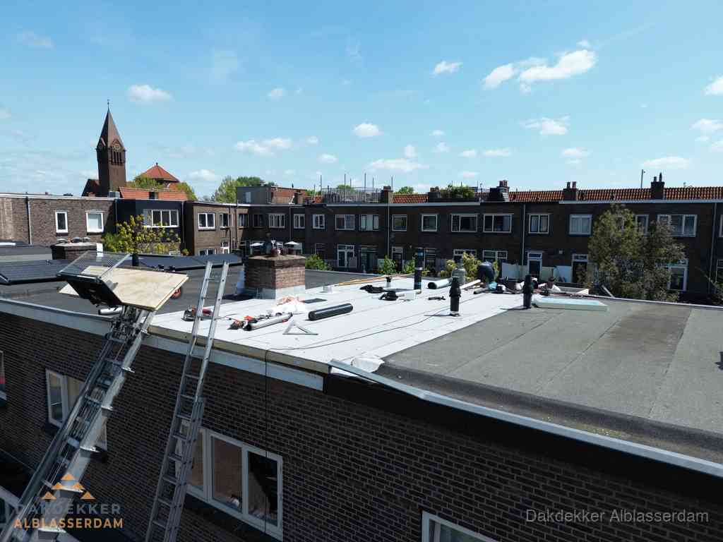 Dakdekkers aan het werk op plat dak in Alblasserdam