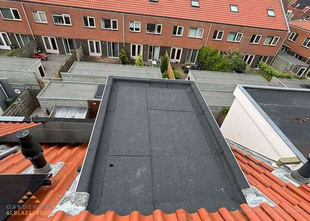 Plat dak met bitumen bedekking naast dakkapel in Alblasserdam