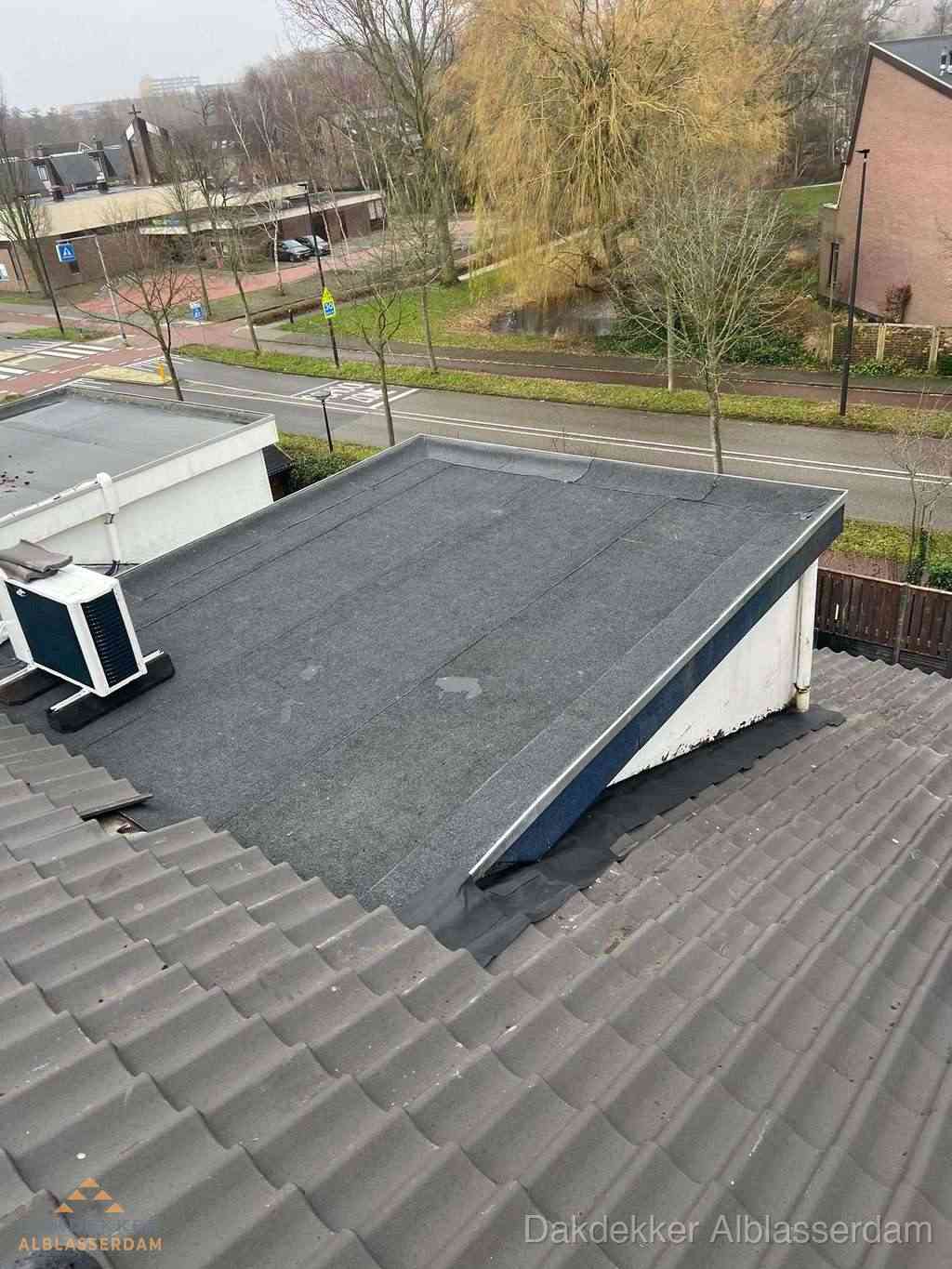 Plat dak met bitumen dakbedekking naast schuin pannendak in Alblasserdam