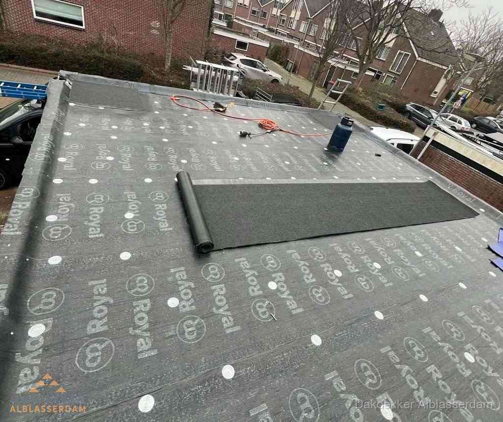 Dakdekker aan het werk met gasbrander op plat bitumen dak in Alblasserdam